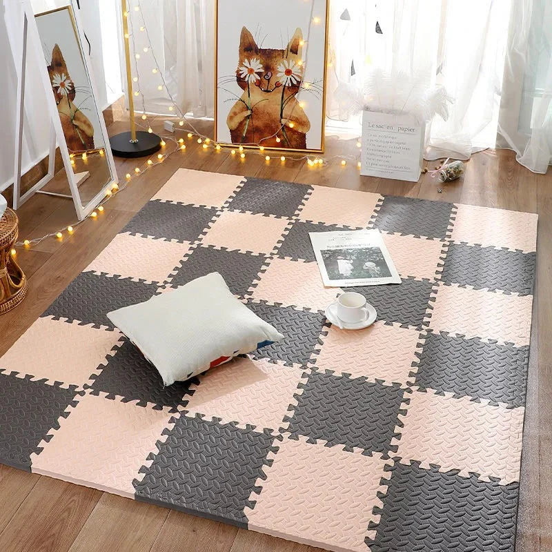 Checkered foam puzzle mat on a wooden floor with a pillow and small table.